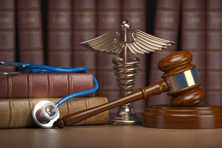 A stethoscope and a judges gavel placed on a table in front of a bookshelf. The combination signifies the overlap of medicine and law when talking about how to defend a Texas Medical Board Review