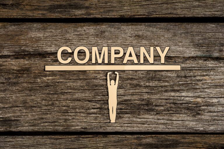 A cut out of a man(a corporate officer with fiduciary duty) is holding up a heavy bar with the word "company" spelled out.