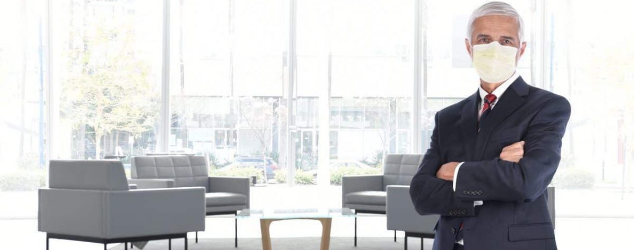 Man wearing mask standing in reception area with chairs widely spaced