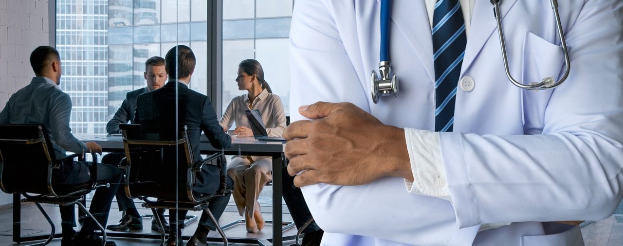 Medical professional standing with arms crossed. In the background, negotiations for agreed order with the TMB are occurring.