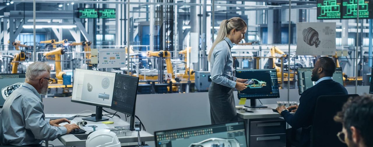 A office of computers and workers in front of a factory floor, which is akin to the conditions in the Tesla collision center